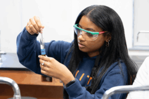 A black female student mixes a chemical in a test tube